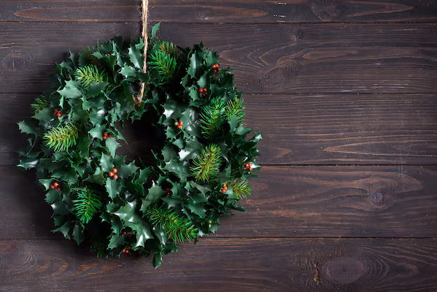 The Southern Door Store 2 Christmas decoration wreath of green leaves and berries holly ilex plant isolated on dark wooden . copyspace Premium Photo